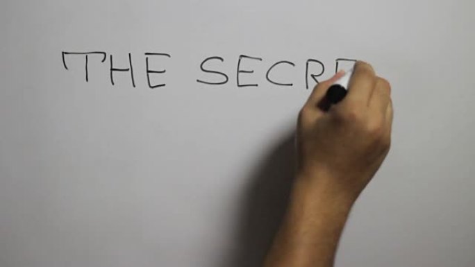 使用黑色记号笔在白板上手写 “秘密继续前进” 消息