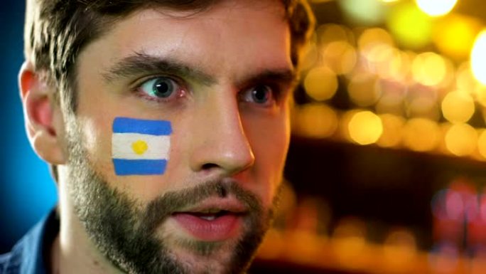 阿根廷足球迷在脸颊上举着旗子，为最喜欢的球队的胜利感到高兴