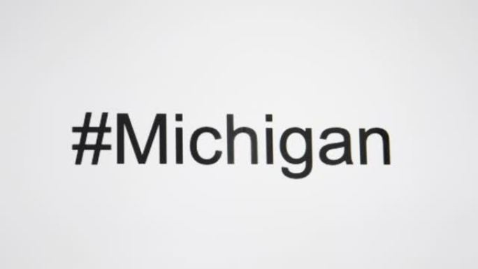 一个人在他们的计算机屏幕上键入 “# Michigan”，然后使用州缩写
