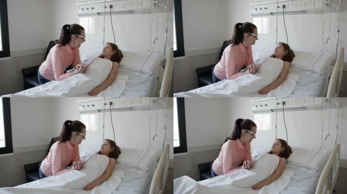 慈爱的母亲试图振作起来，她害怕的女儿躺在医院的病床上说话和微笑