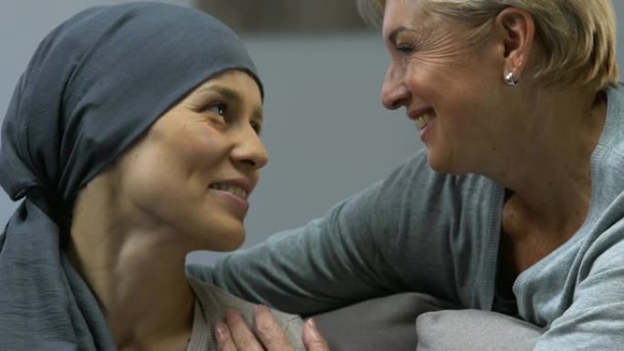 母亲亲吻患有癌症的爱心女儿，在化疗期间提供支持