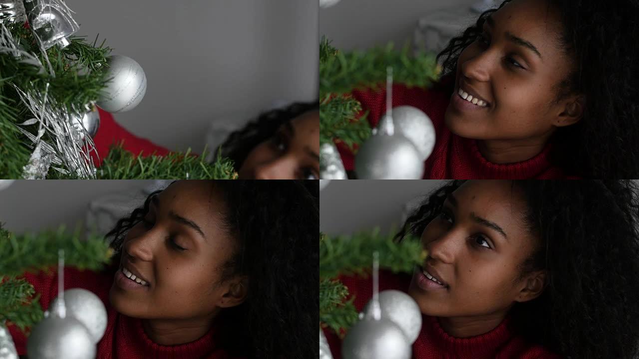 美丽的女人装饰她的圣诞树，然后看着相机非常好玩
