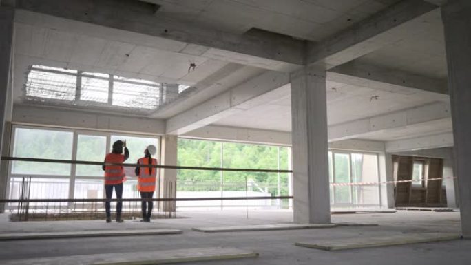 LD女服务员和女建筑师站在建筑物中，一边交谈，一边检查施工细节