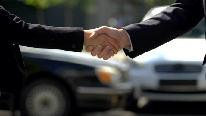 男人和女人在汽车的背景下握手，汽车交换，购买