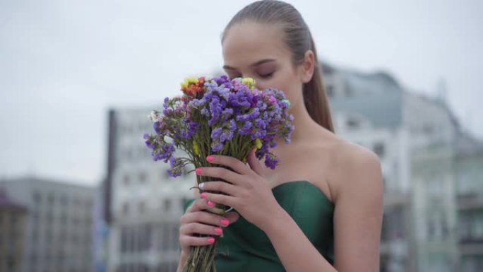 美丽的女孩穿着别致的衣服站在一束芬芳的野花。