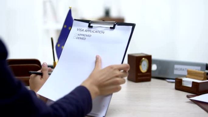 大使馆工作人员批准签证申请，欧盟旗帜在桌上，法律