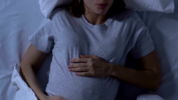 孕妇抱著肚子在床上翻身睡不舒服