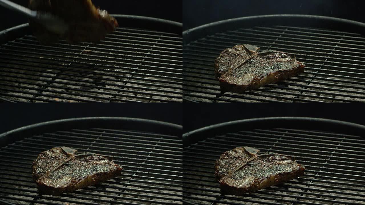 一对钳子将一块做得很好的牛排翻转到烧烤架的金属炉排上