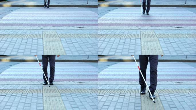 用白色拐杖穿过街道的盲人男性，使用触觉瓷砖在城市中导航