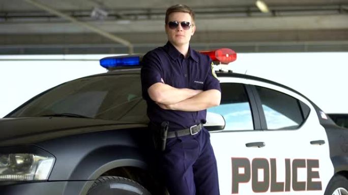 戴着墨镜的武装警察站在巡逻车旁，危险的职业