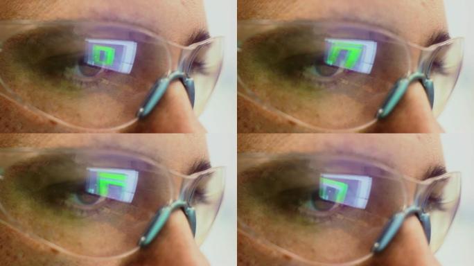 在室内办公室的防护眼镜中反射计算机屏幕的高加索技术人员的眼睛的特写镜头
