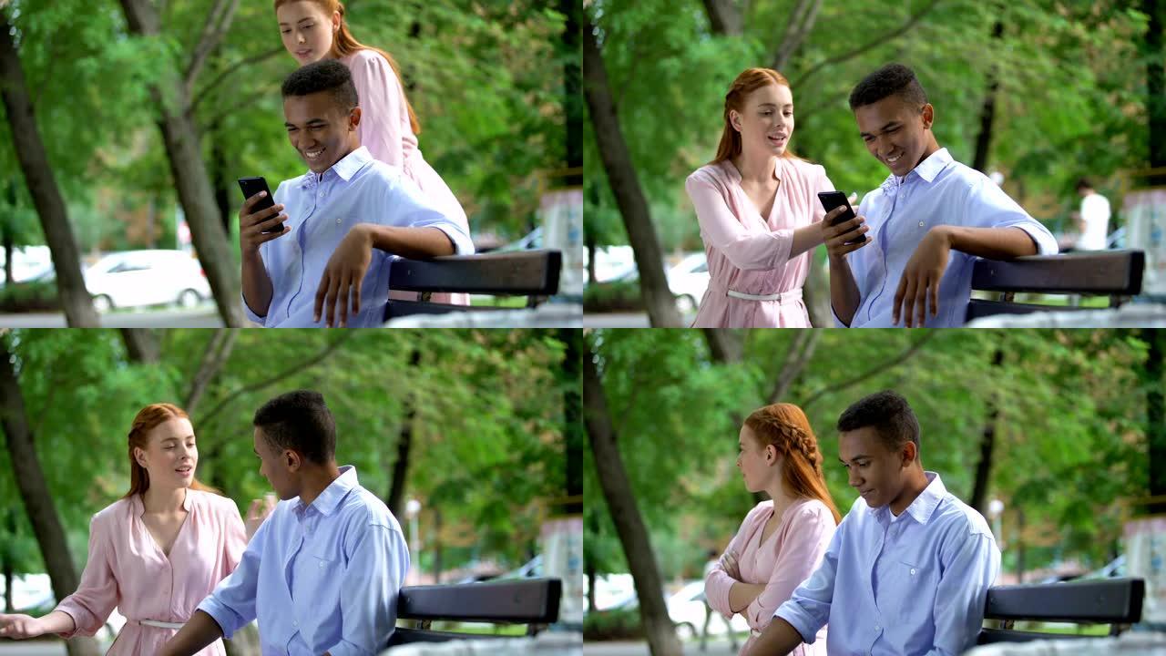 得罪的少女注意到她的男朋友在公园里聊天智能手机，嫉妒