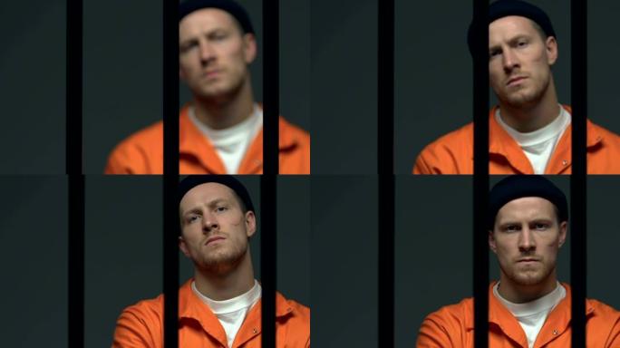 脸上有伤疤的囚犯在监狱铁窗后自信地看着镜头