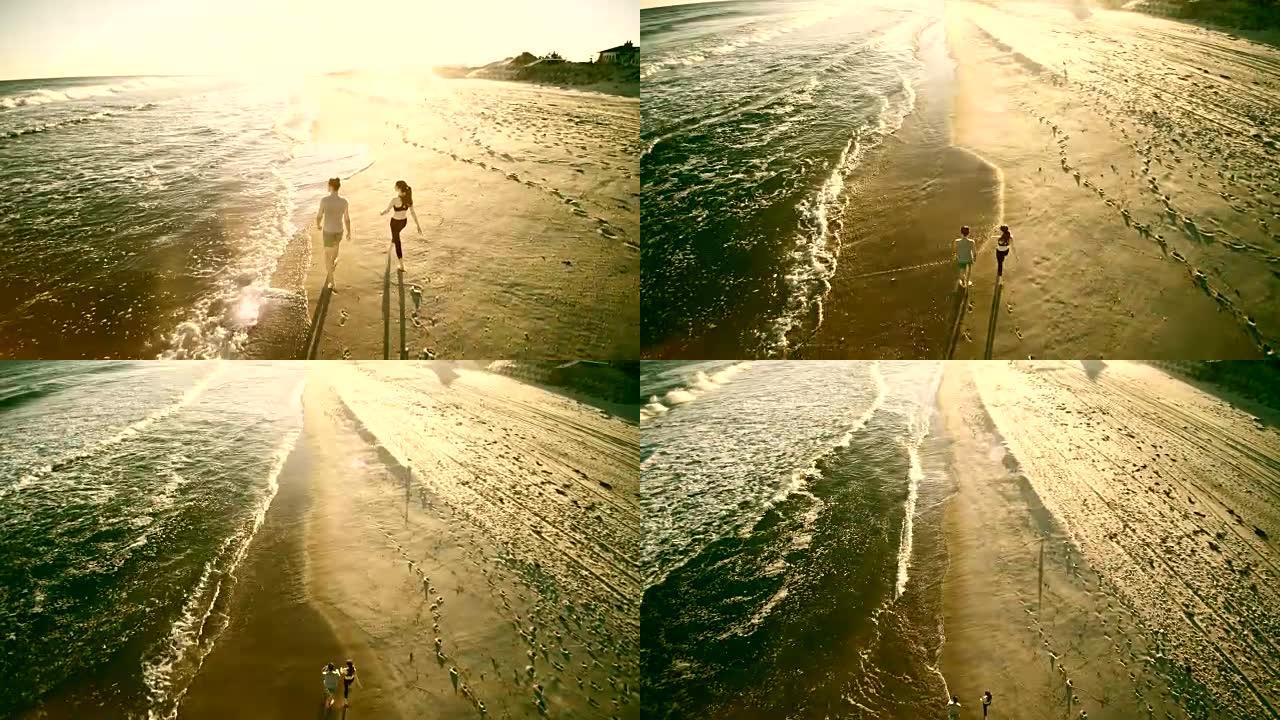 年轻人和十几岁的女孩一起散步，在长岛的海滩上聊天。摄像机从非常低的高度爬升到正上方的航拍镜头。