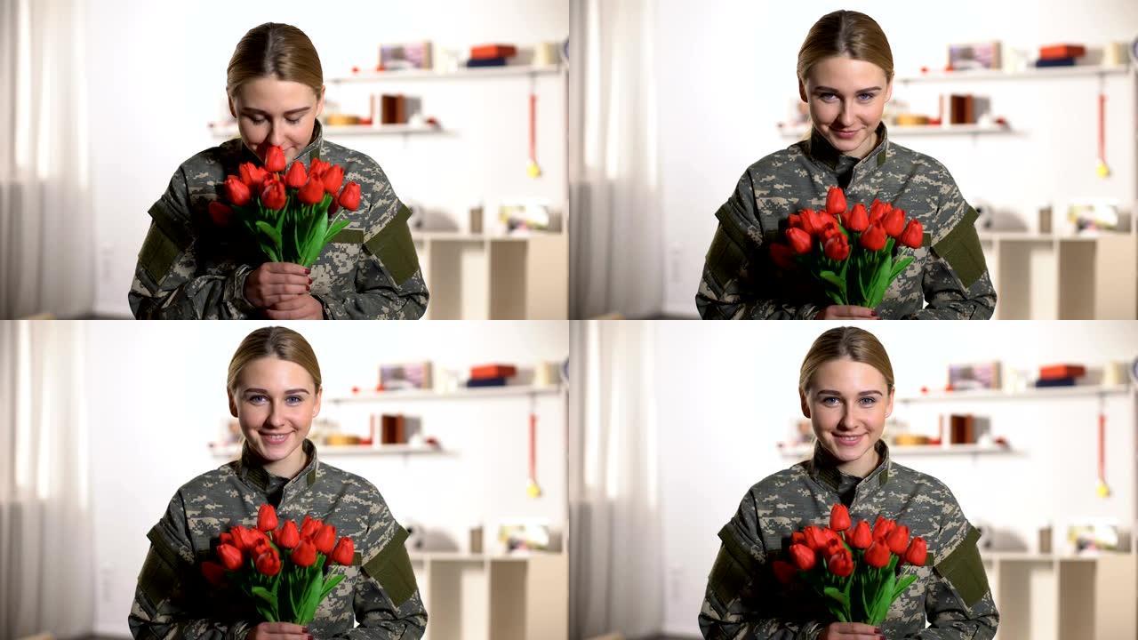 快乐的身着制服的女兵闻着郁金香花束的香气微笑着