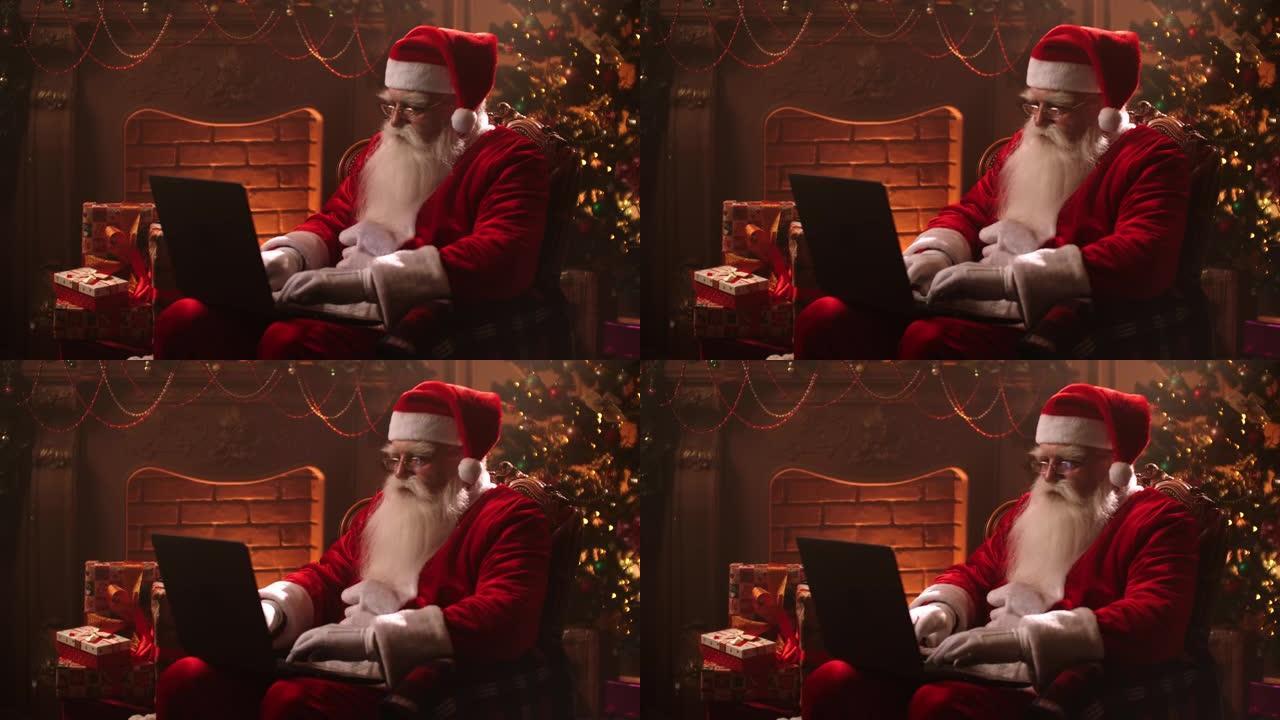 圣诞老人的魔术室坐在家里的光束中，在圣诞节前夕，壁炉和圣诞树的背景下，坐在互联网上的笔记本电脑上打字