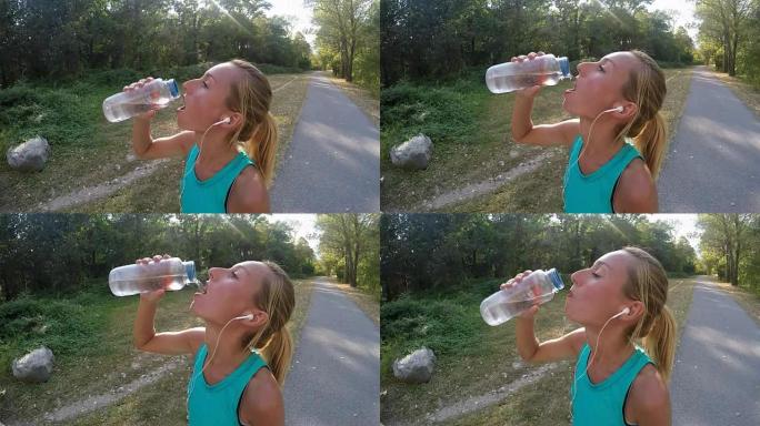 美丽而运动的年轻女子在户外慢跑后喝水