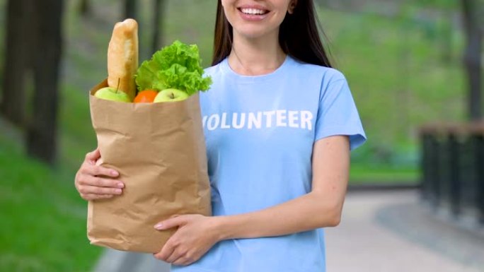 志愿者带着食品包装在户外微笑，为挨饿的人捐款