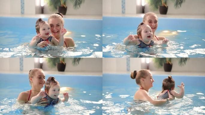 游泳池里的年轻妈妈和她的小女儿在慢动作中玩耍。从事积极生活方式的体育家庭