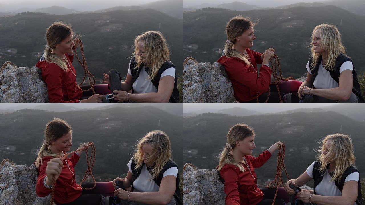 女性登山者在日出时在山顶上组织绳索和装备