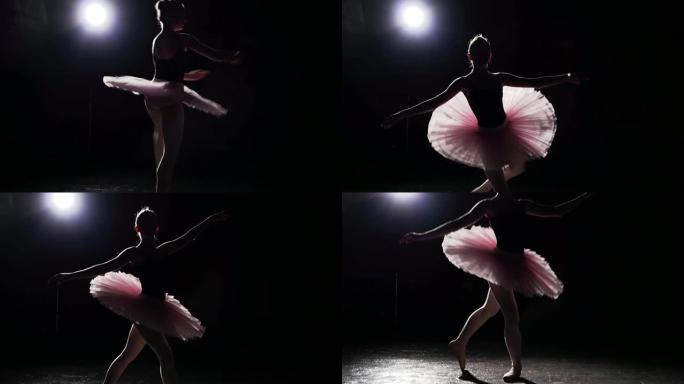 在工作室里，年轻而优雅的芭蕾舞演员在黑色背景上的脚尖芭蕾舞鞋上跳舞。女人展示经典芭蕾舞剧。慢动作。