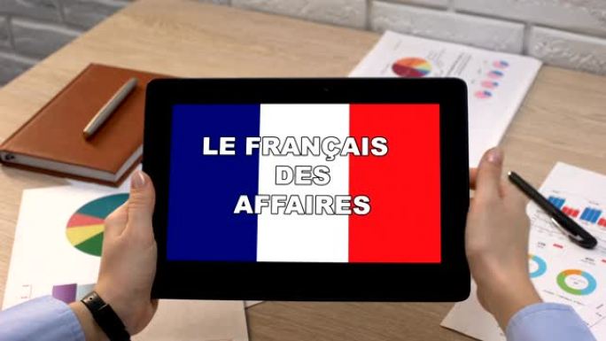 商务法语应用程序反对女性手中的平板电脑上的旗帜，教程