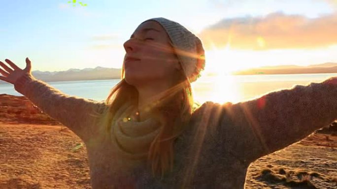 年轻女子在湖边放松，双臂伸出