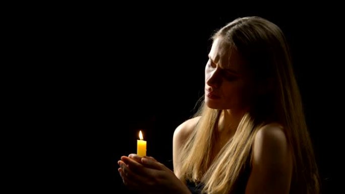 宗教妇女在祈祷，深切的信仰和悔改后吹灭蜡烛