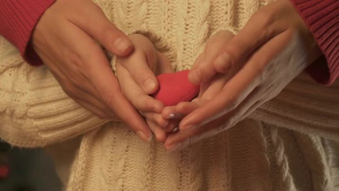 儿童和妇女手握玩具的心，父母的爱和关怀的概念
