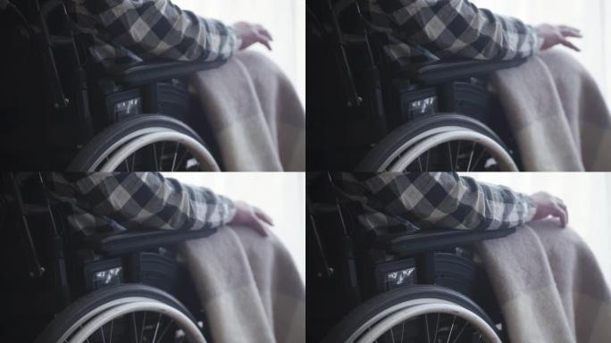 轮椅的特写镜头，残疾的白人老人坐在轮椅上。成熟的瘫痪的家伙使用移动设备。残疾，老人，生活方式。