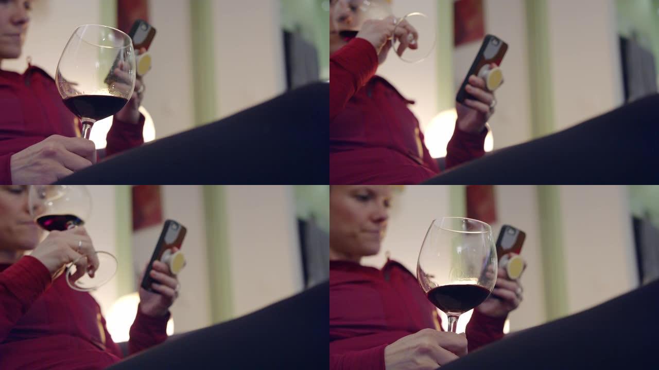 女人在沙发上放松的细节，拿着智能手机和一杯葡萄酒