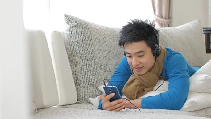 男人喜欢在家里放松时间听音乐和触摸智能手机，生活方式和放松理念
