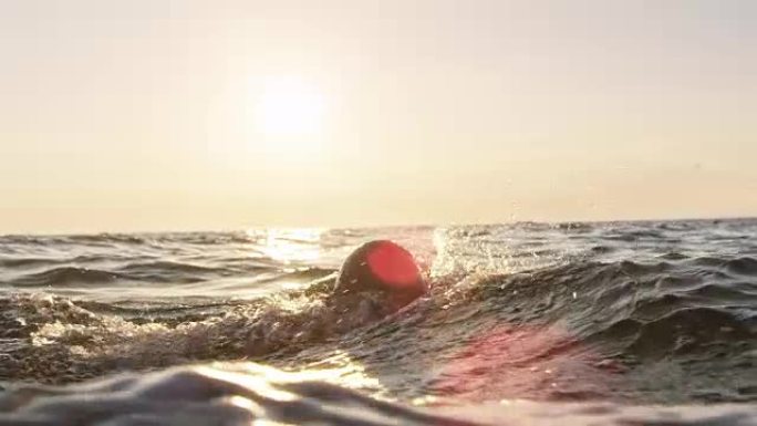 SLO MO TS公开水域游泳者在阳光下在海上游泳