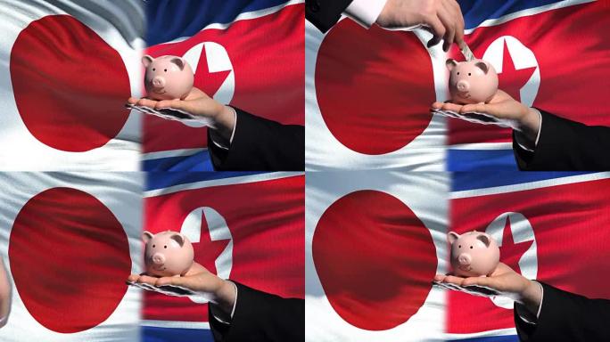 日本投资朝鲜手把钱放在存钱罐里，旗帜背景