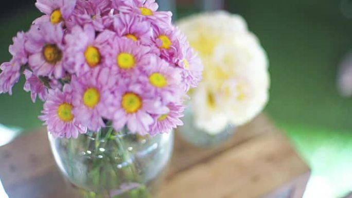 木制桌子上花瓶里的粉色菊花花。