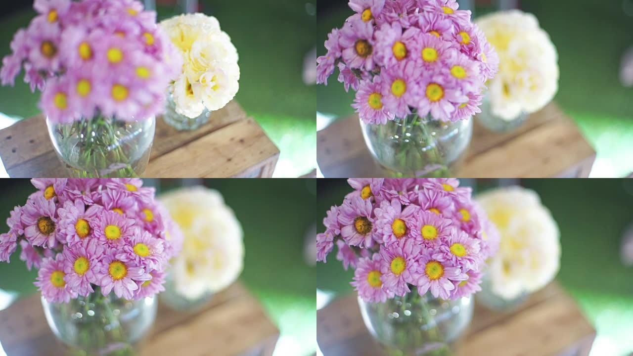 木制桌子上花瓶里的粉色菊花花。