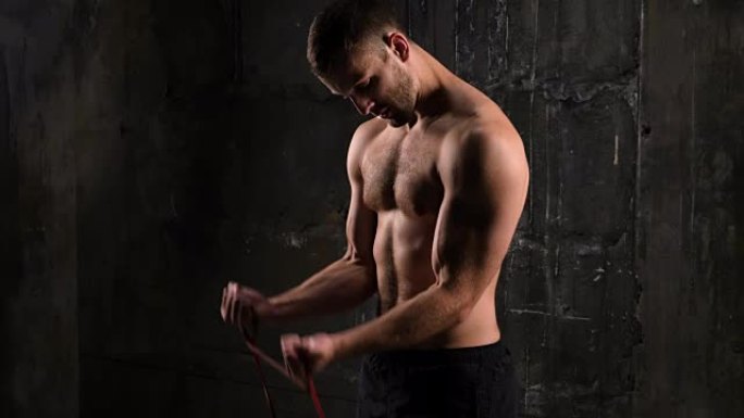 赤裸上身的年轻强壮的运动员用橡皮筋锻炼