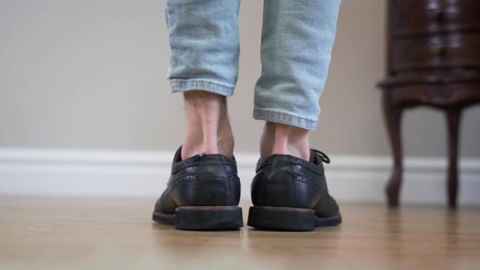 黑色broggi靴子的特写镜头转向两侧。无法辨认的高加索成年男子转脚离开。鞋类，配饰，时尚。