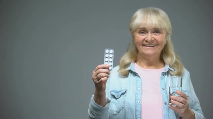 微笑的老年女士显示药丸药物质量，免疫力增强药物
