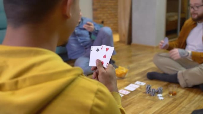 混血男子握着软弱的手，在家里和朋友玩扑克，冒险