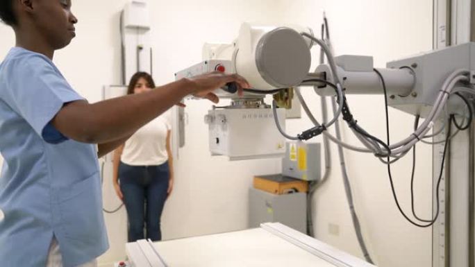 黑人女性放射科医生在病人准备就绪时调整x光机