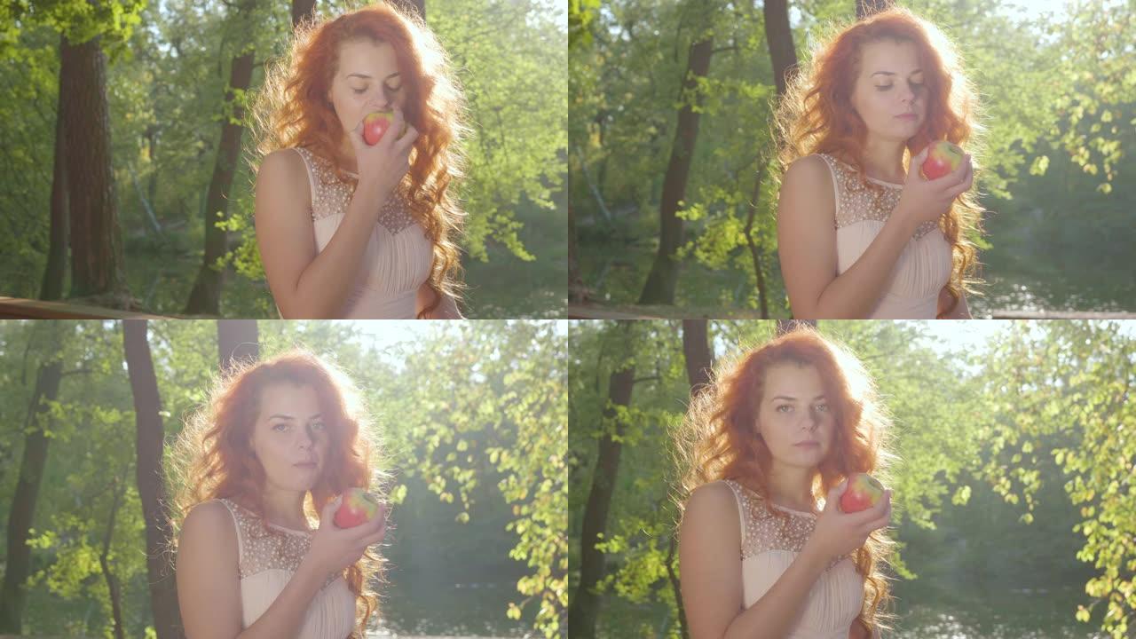 美丽的白衣白人妇女在秋天的公园里吃红苹果。特写视图。