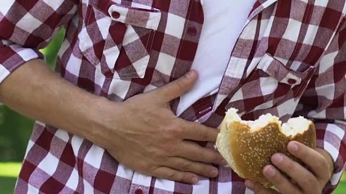 饥饿的人吃不健康的汉堡感觉胃痛胆囊炎，胃炎