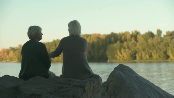 两名高级妇女坐在湖附近的公园里聊天，与朋友度过了最美好的时光