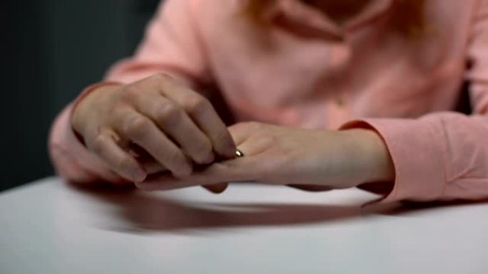 心烦意乱的女士从手指上拔出结婚戒指，破裂的关系，不幸的婚姻
