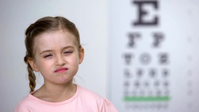 小女孩试图阅读视程表中的字母，近视诊断