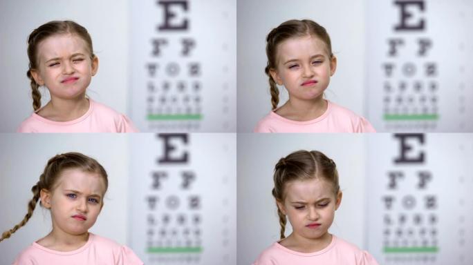 小女孩试图阅读视程表中的字母，近视诊断