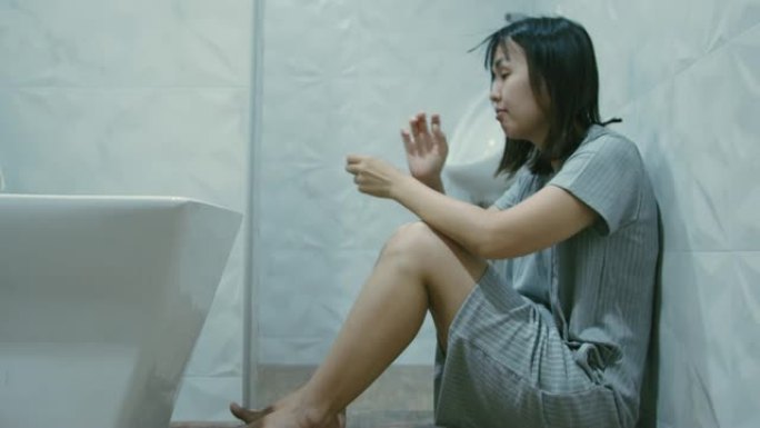 悲伤的女人坐在浴室的地板上，妊娠试验呈阴性