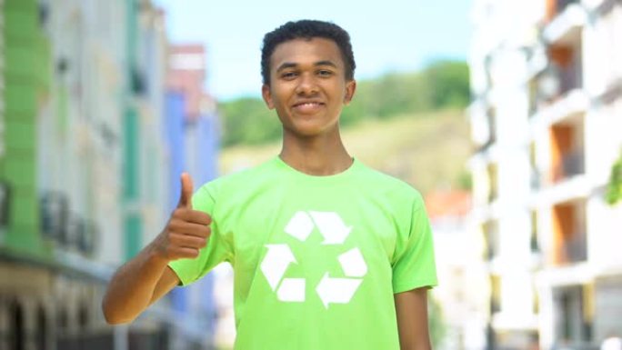 欢乐的混血少年在回收符号t恤上竖起大拇指，生态