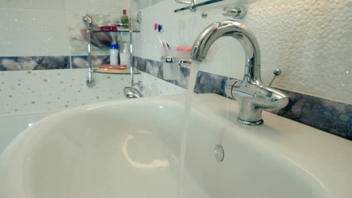 在浴室里，一个漂亮、闪亮的水龙头将水流入脸盆